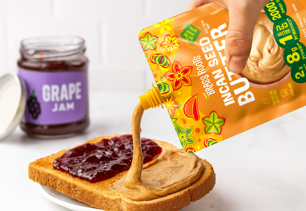 Hand spreading peanut butter on a slice of bread with grape jam, using a 'Bare Roots' product.